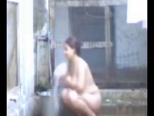 Una dama india tomando su baño afuera